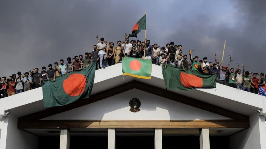 Anti-government protestors display Bangladesh's national flag after storming prime minister Sheikh Hasina's residence, Dhaka, August 5, 2024