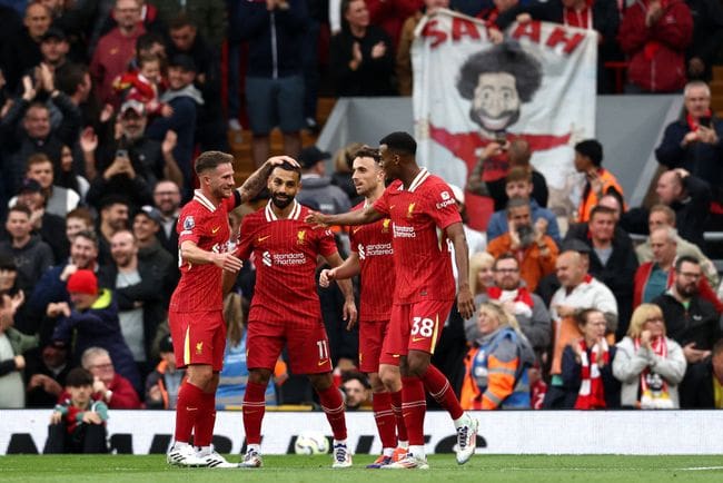 Liverpool's Egyptian striker #11 Mohamed Salah (2L) celebrates with teammates after scoring the team's second goal during the English Premier League football match between Liverpool and Brentford at Anfield in Liverpool, north west England on August 25, 2024. (Photo by Darren Staples / AFP) / RESTRICTED TO EDITORIAL USE. No use with unauthorized audio, video, data, fixture lists, club/league logos or 'live' services. Online in-match use limited to 120 images. An additional 40 images may be used in extra time. No video emulation. Social media in-match use limited to 120 images. An additional 40 images may be used in extra time. No use in betting publications, games or single club/league/player publications. / (Photo by DARREN STAPLES/AFP via Getty Images)